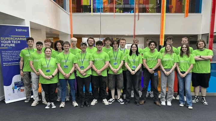 A group in bright green Kainos CodeCamp shirts inside a colourful atrium