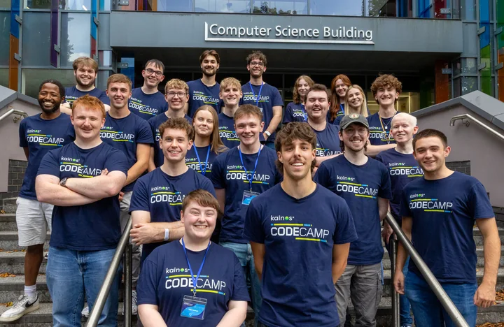 A group in navy Kainos CodeCamp shirts on the steps outside the Computer Science Building