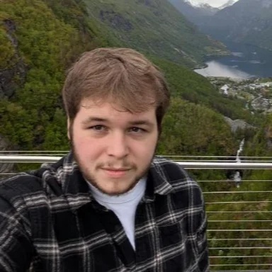 Dylan outdoors with a mountain landscape behind him